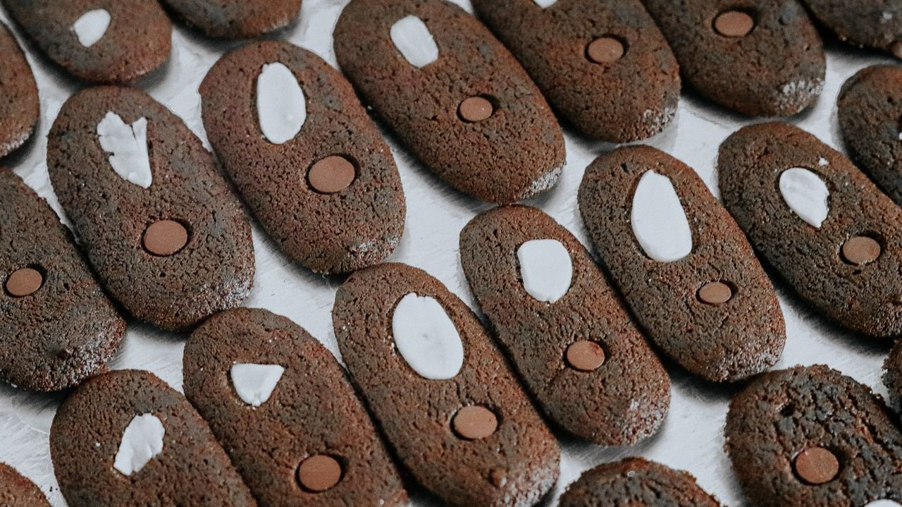 services-04 Close-up of chocolate cookies topped with almonds and chocolate chips, perfect for a sweet treat.